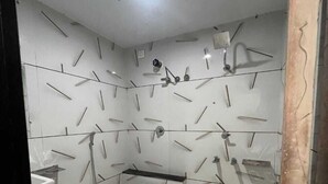 Un bagno piccolo e compatto con un water bianco, un lavandino e una doccia. Le pareti sono rivestite di piastrelle con un motivo di linee e forme.