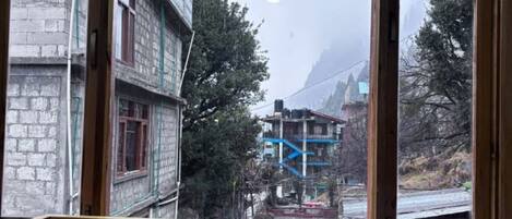 A room with a large window overlooking a mountainous area with buildings and trees.