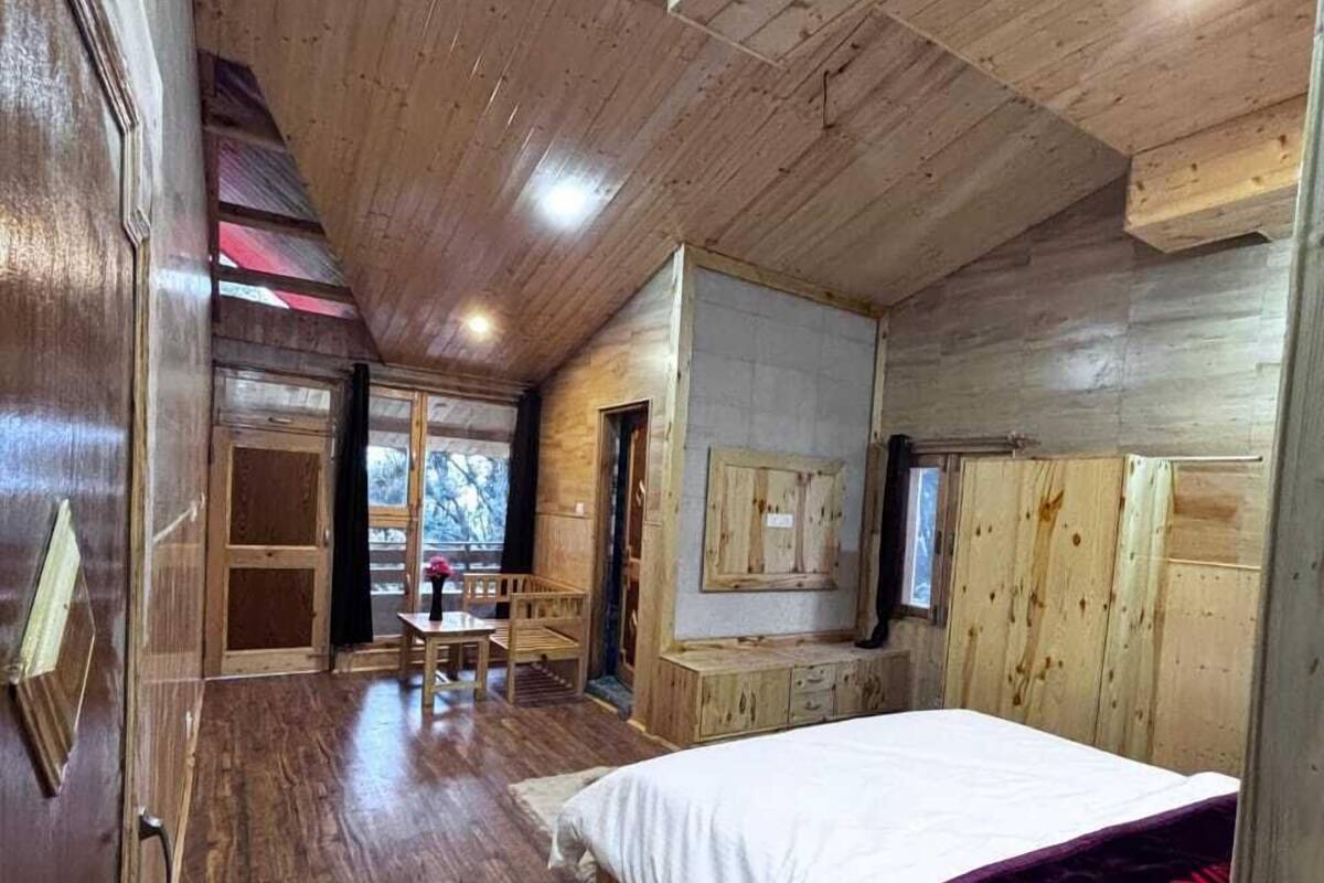Ein Schlafzimmer einer Holzhütte mit einem Bett, einem Schreibtisch und einem Stuhl.