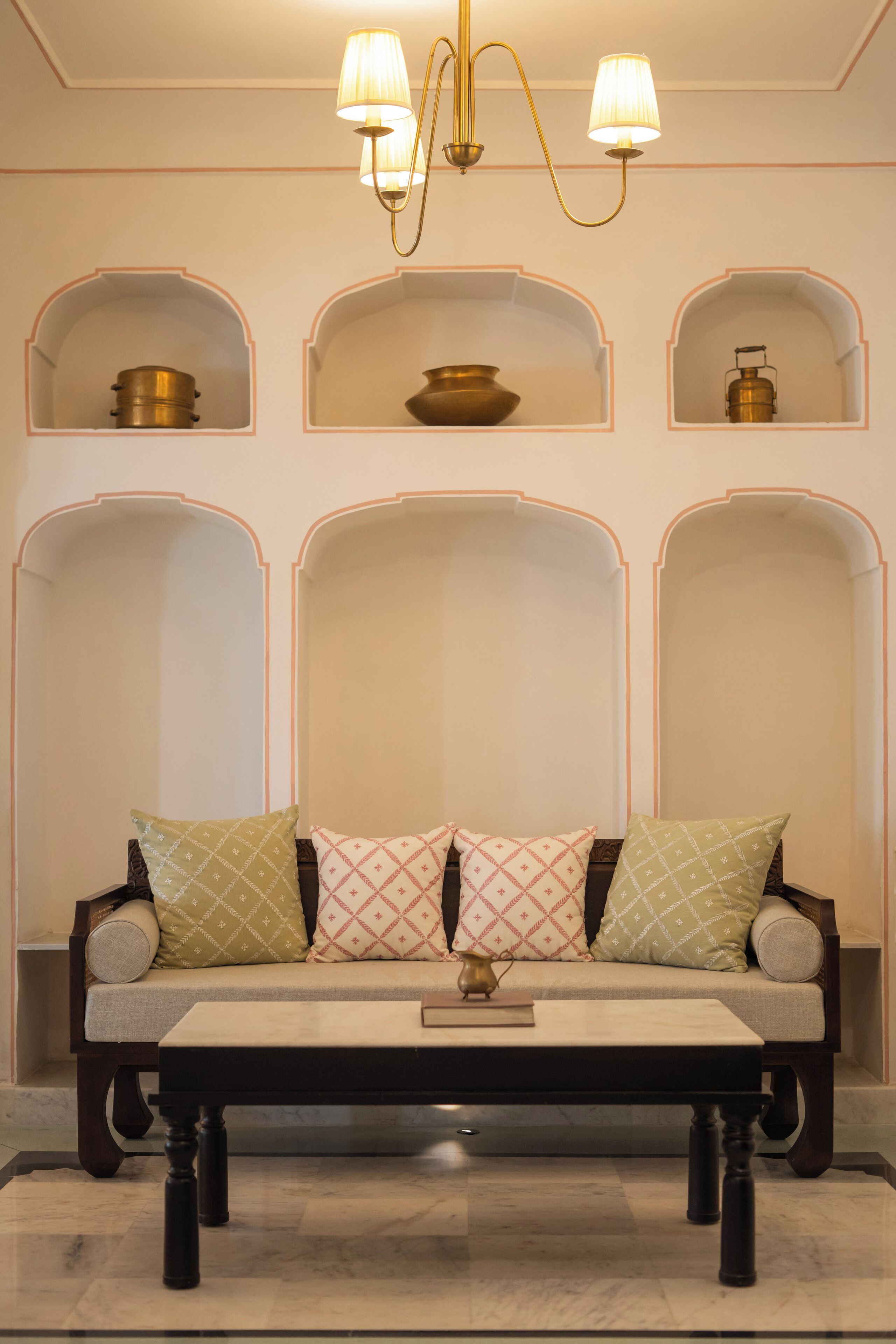 A sofa with patterned cushions, a small table, and a chandelier.