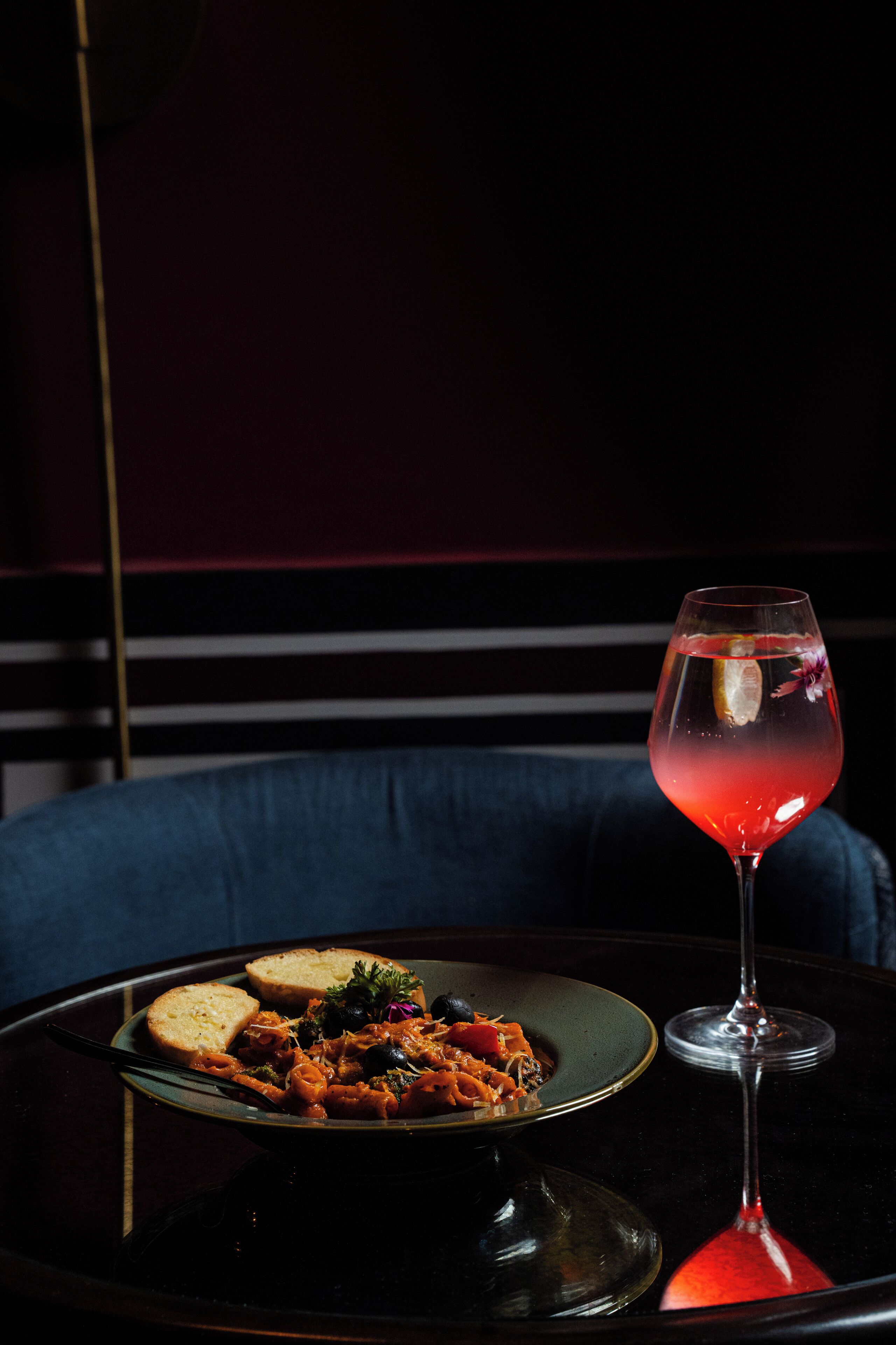 A table with a plate of food and a glass of red drink.