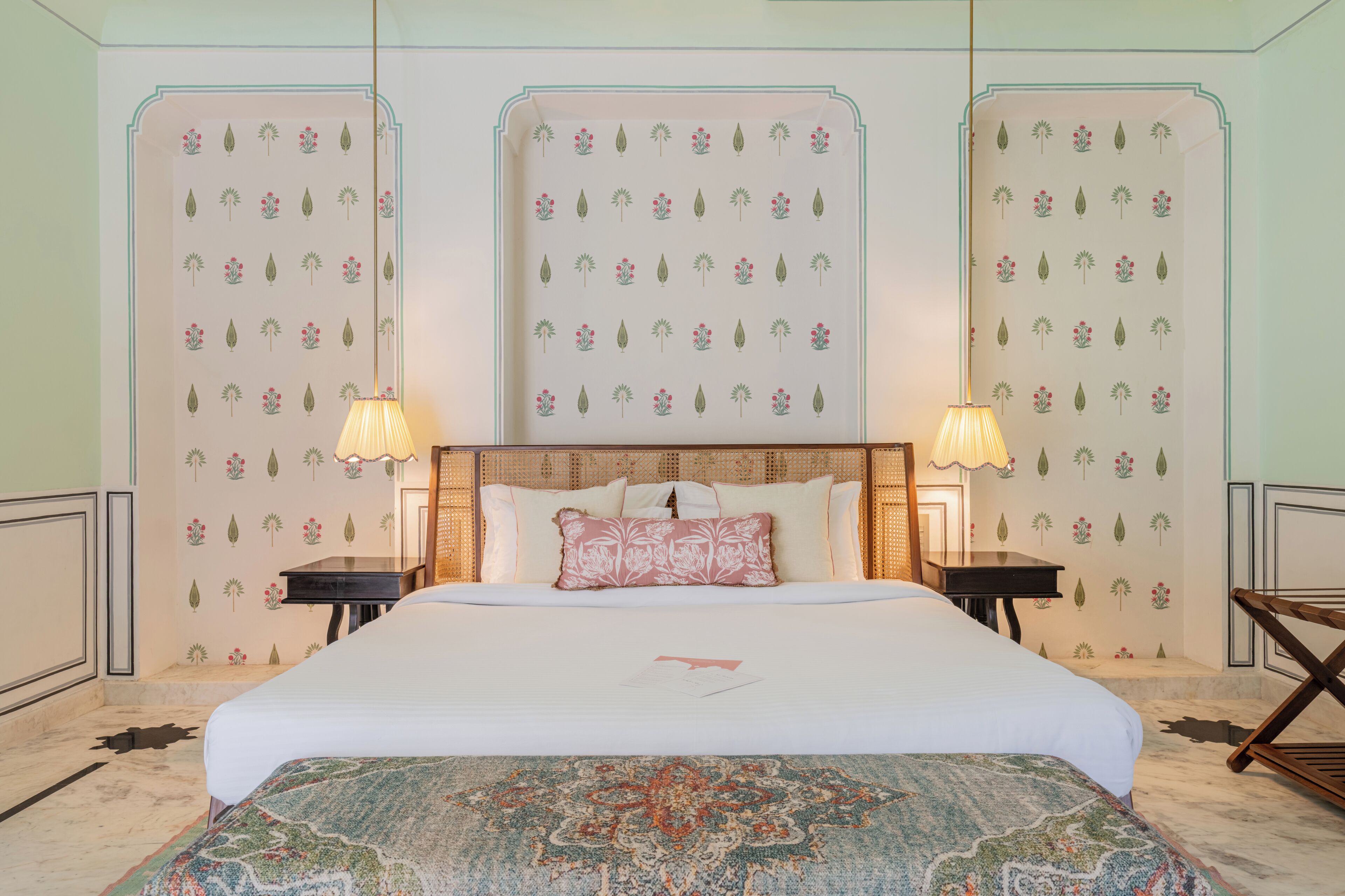 A neatly arranged bedroom with a large bed, two bedside tables, and a patterned wall.