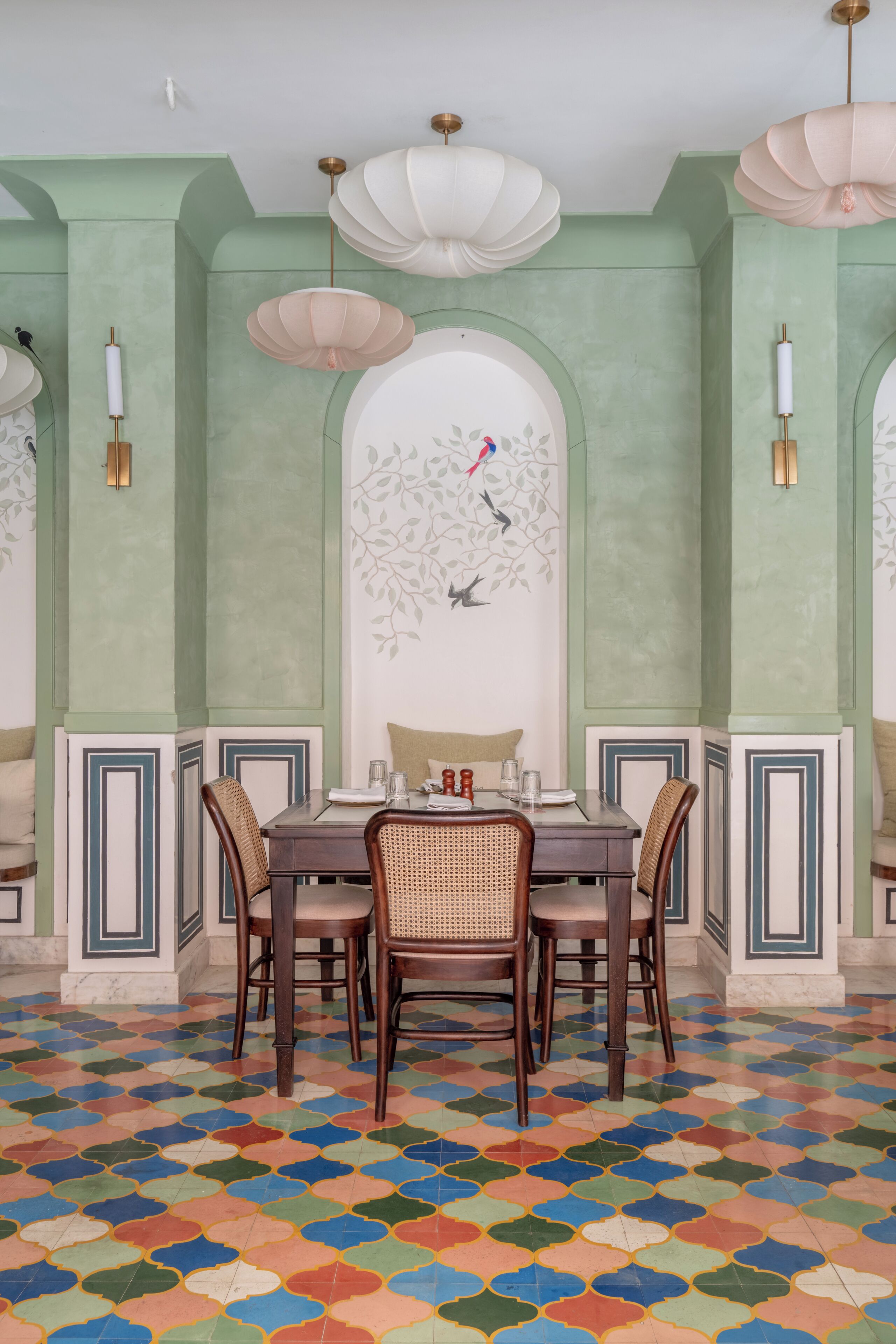 Comedor con una mesa dispuesta para cuatro personas, rodeada de sillas y un suelo de baldosas coloridas.