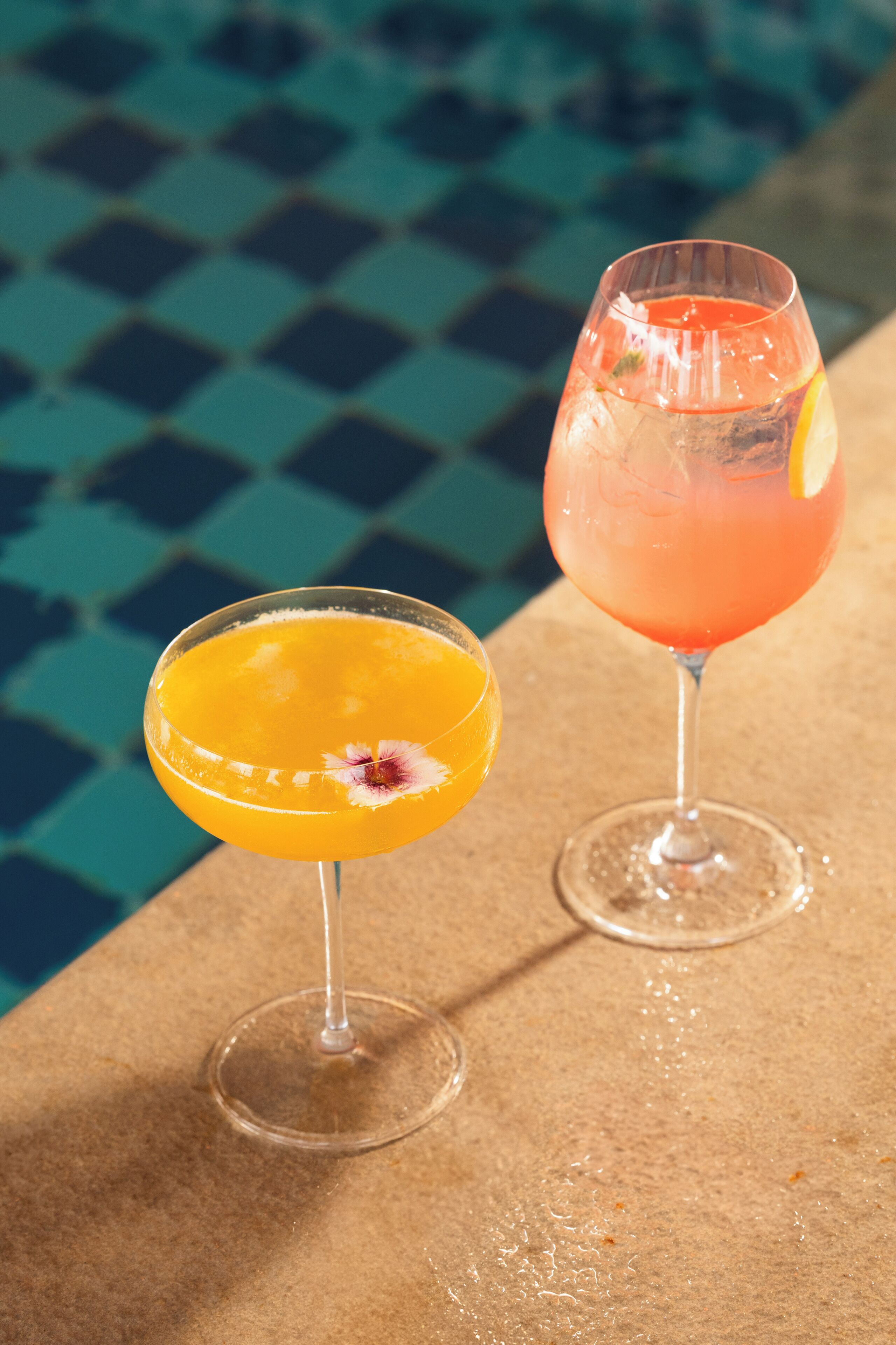 Twee cocktails op een tafel bij een zwembad.