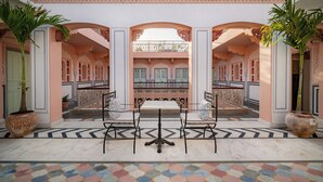 Ein traditionelles Interieur mit einem zentralen Tisch und Stühlen, verzierten Bögen und einem gemusterten Boden.
