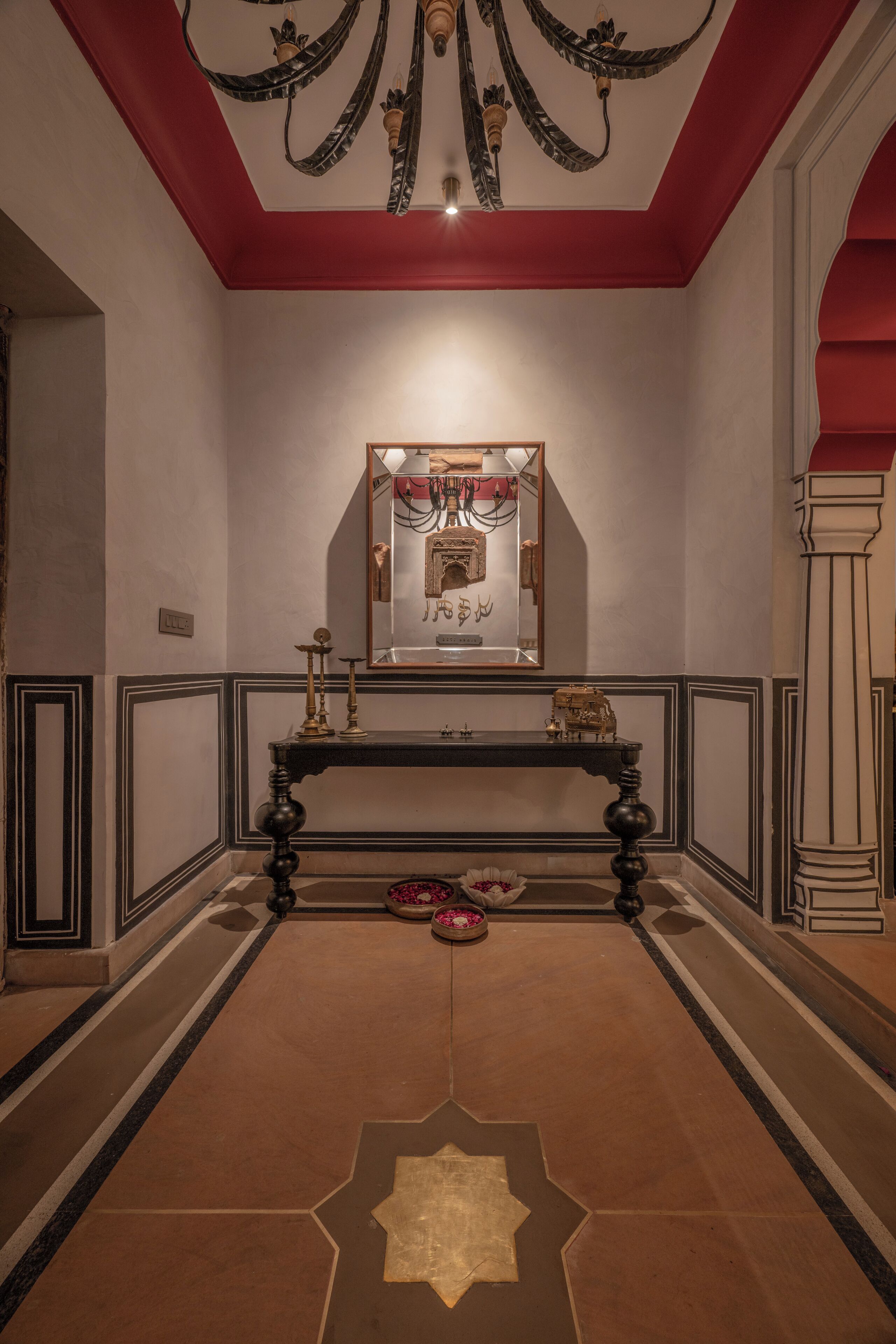 A hallway with a red ceiling, a black console table, and a mirror above it.