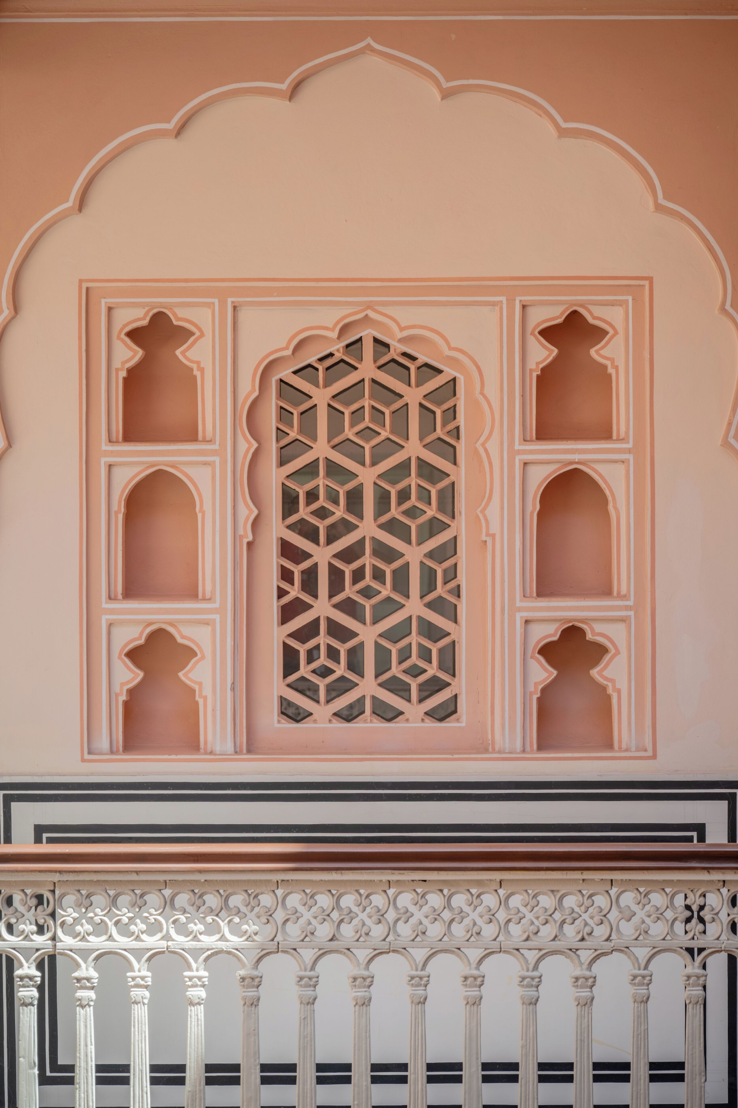 A traditional architectural design with a geometric window pattern and ornate balcony railings.