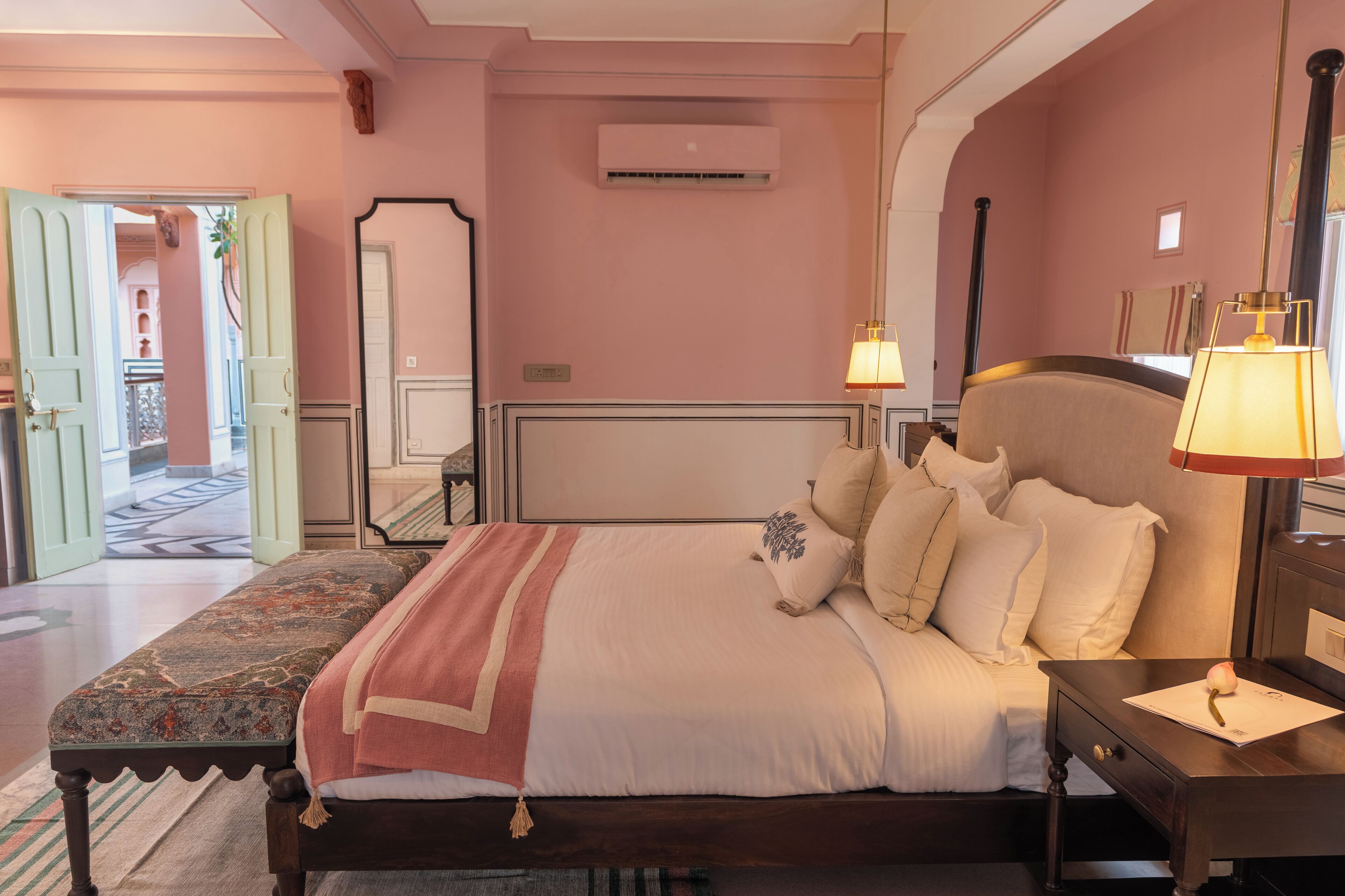 A bedroom with a large bed, bedside lamps, a nightstand, and a view of the hallway.
