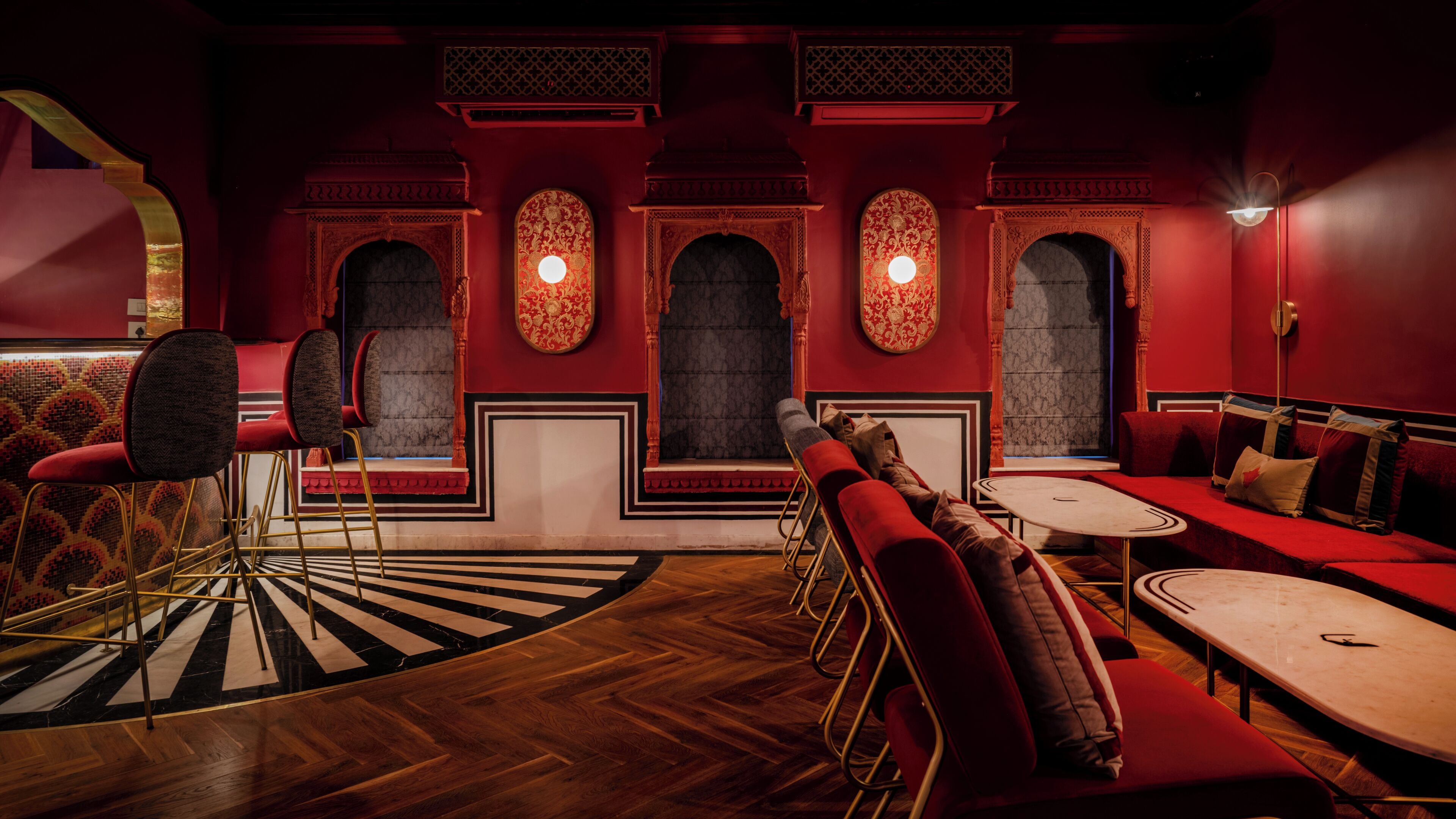 A room with red walls, a patterned carpet, and a seating area with red sofas and a small table.