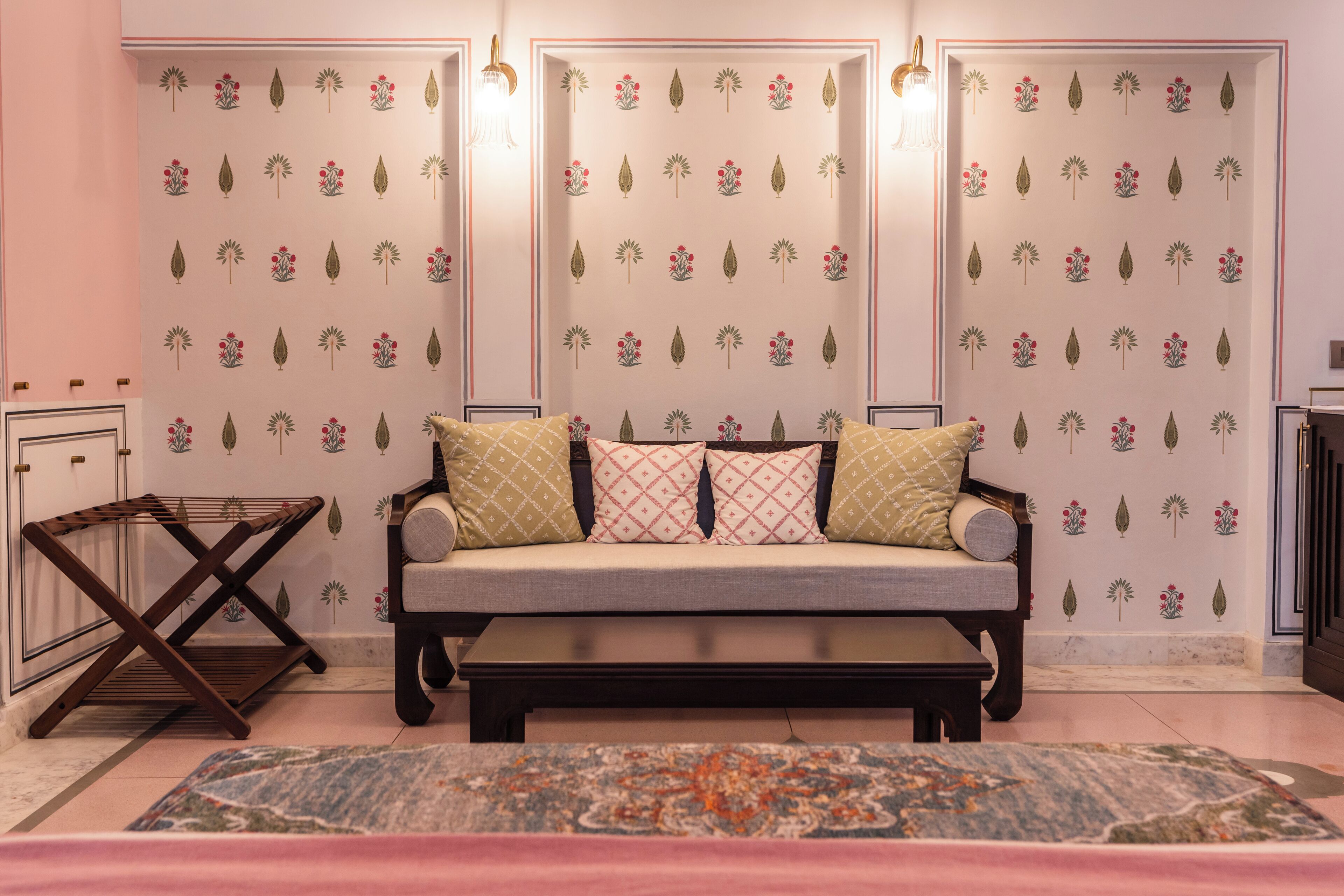 A cozy room with a sofa, patterned wallpaper, and a decorative rug.