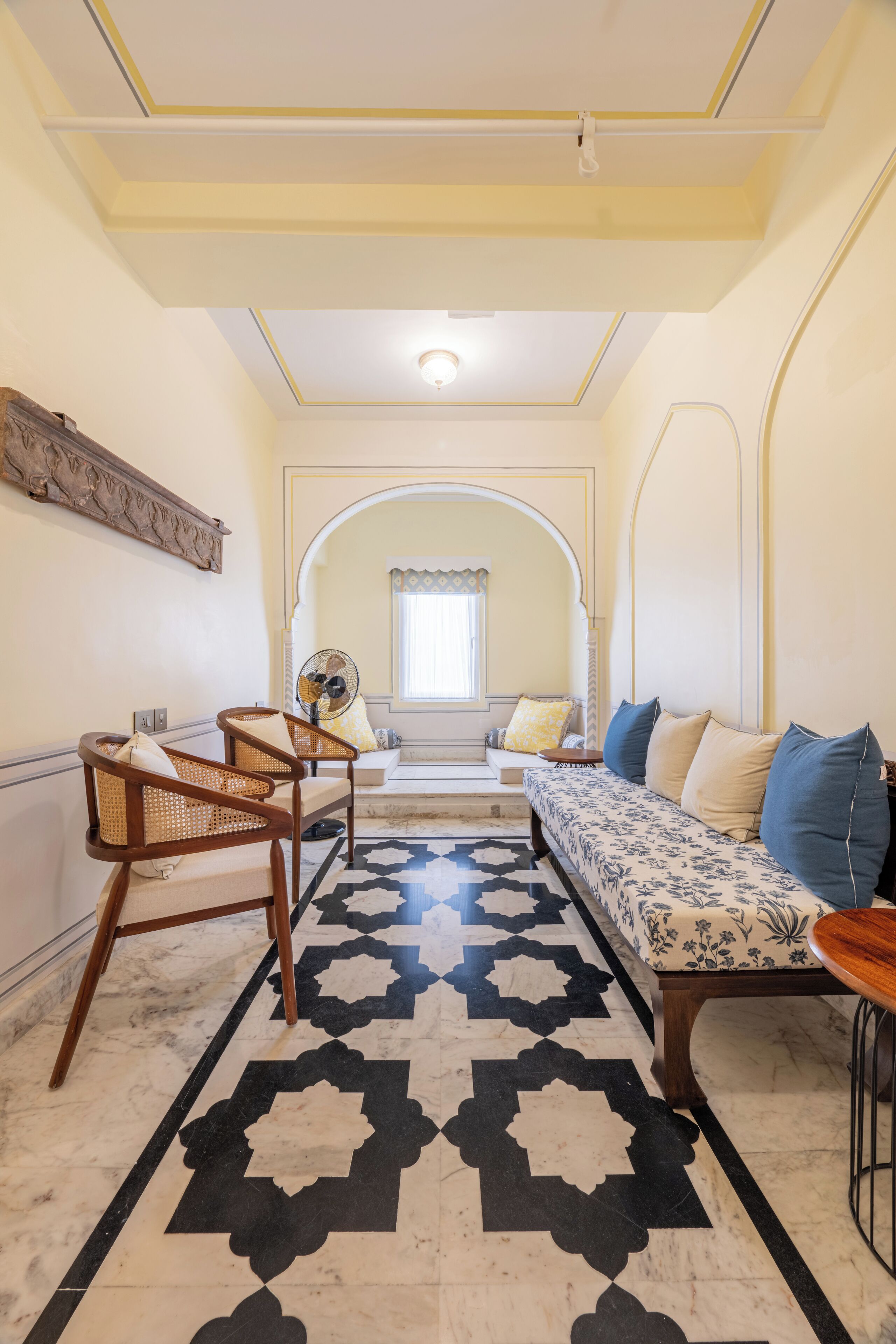 A room with a sofa, chairs, a patterned rug, and a fan.