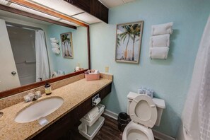 Une salle de bain équipée d’un lavabo, d’un miroir, de toilettes et de serviettes.