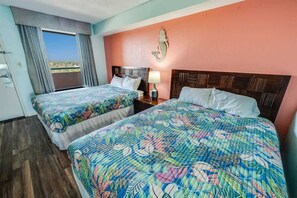 Une chambre d’hôtel avec deux lits, une fenêtre avec des rideaux, une table de chevet avec une lampe et un élément décoratif mural.