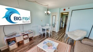 Amplia sala de estar con comedor, un televisor mostrando 'BIG FISH Rentals' y una zona de estar acogedora.