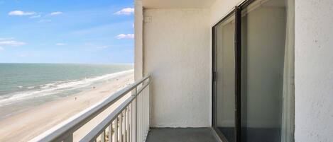 A balcony with a view of the beach and ocean.