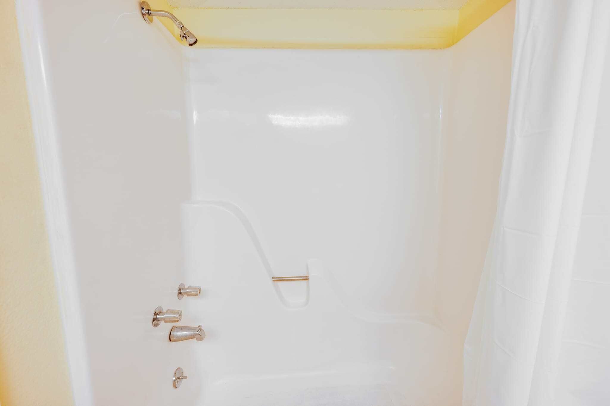 Une baignoire blanche avec un pommeau de douche et deux robinets.