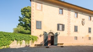A building with a symmetrical facade, a central entrance with a decorative arch, and shutters on the windows. - Villa Ott in Crespina (Lorenzana)