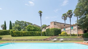 A swimming pool with a brick deck, surrounded by well-maintained hedges and palm trees. - Villa Ott in Crespina (Lorenzana)