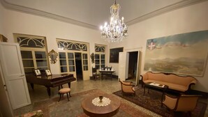 A spacious living room with a grand piano, a round coffee table, and a sofa. - Villa Ott in Crespina (Lorenzana)