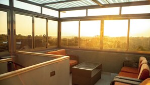 A sunlit room with large windows, wicker furniture, and a view of the cityscape. - Kambi Mstuni Resort (Ndaragwa)