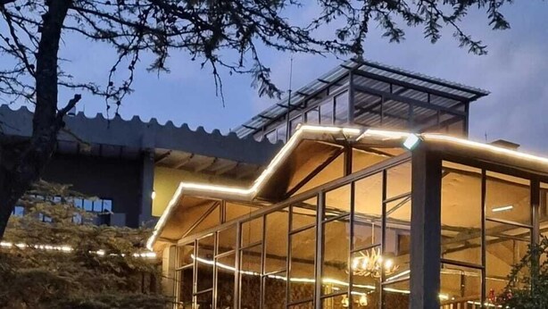 A modern building with a glass facade, stone steps leading to the entrance, and a metal roof structure. - Kambi Mstuni Resort (Ndaragwa)