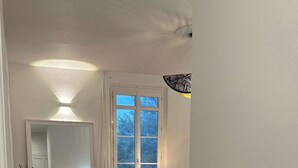 Una habitación amplia con un ventanal grande, una silla, una lámpara y un radiador.