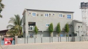 A multi-story building with a grey facade, several windows, and air conditioning units. - Godfather's Place (Abuja)