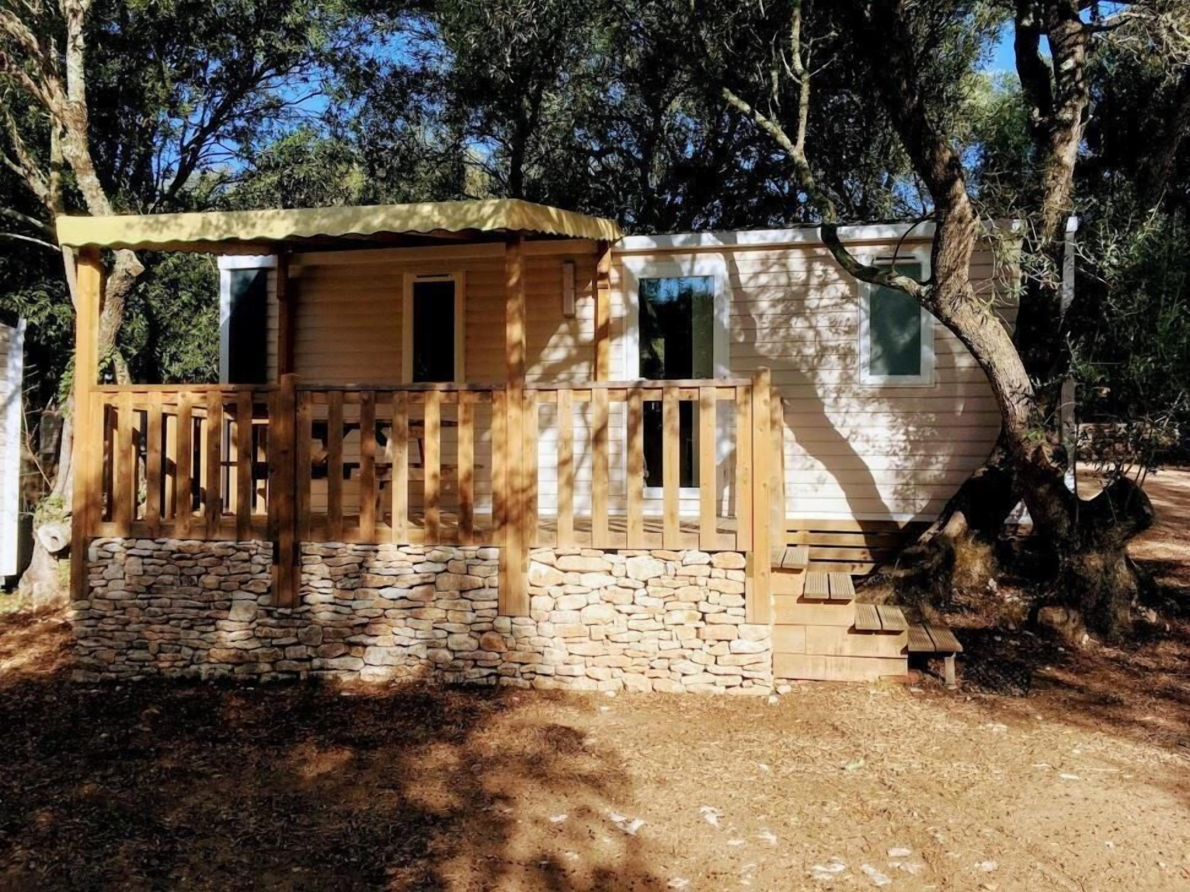 A wooden cabin with a stone foundation, a wooden porch, and a small window.