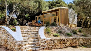 Een moderne chalet met een stenen keerwand, een houten terras en een stenen trap naar de ingang.