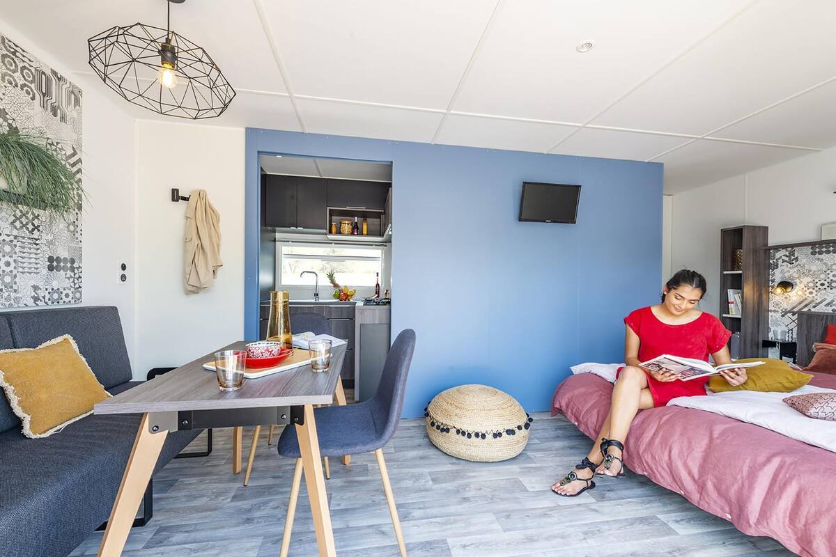Moderni huone, jossa on ruokapöytä, tuoleja, sohva, sänky ja keittiöalue.