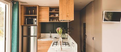 A modern kitchen with wooden cabinets, a stainless steel refrigerator, a microwave, and a gas stove.