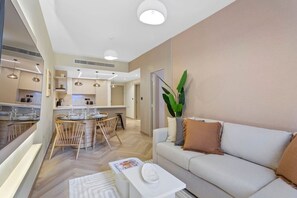 Uma sala de estar moderna com sofá, mesa de centro e área de jantar com mesa e cadeiras.