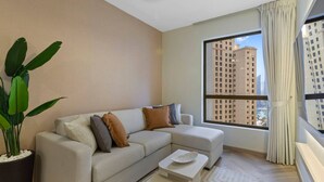 Ein modernes Wohnzimmer mit einem beigefarbenen Sofa, einem Couchtisch und einem großen Fenster mit Vorhängen.