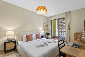 A hotel room with a bed, bedside lamps, a laptop on a wooden table, and a view of the outside through a large window.