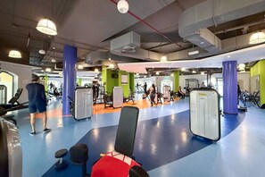 A gym with exercise equipment, a blue and orange floor, and green walls.