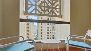 Ein Balkon mit zwei Stühlen und einem kleinen Tisch, mit Blick auf eine Skyline mit hohen Gebäuden.