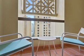 A balcony with two chairs and a small table, overlooking a cityscape with tall buildings.