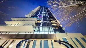 Un immeuble moderne de grande hauteur, doté d’une façade en verre, de grandes fenêtres et d’une entrée imposante, caractérisée par un design architectural unique.