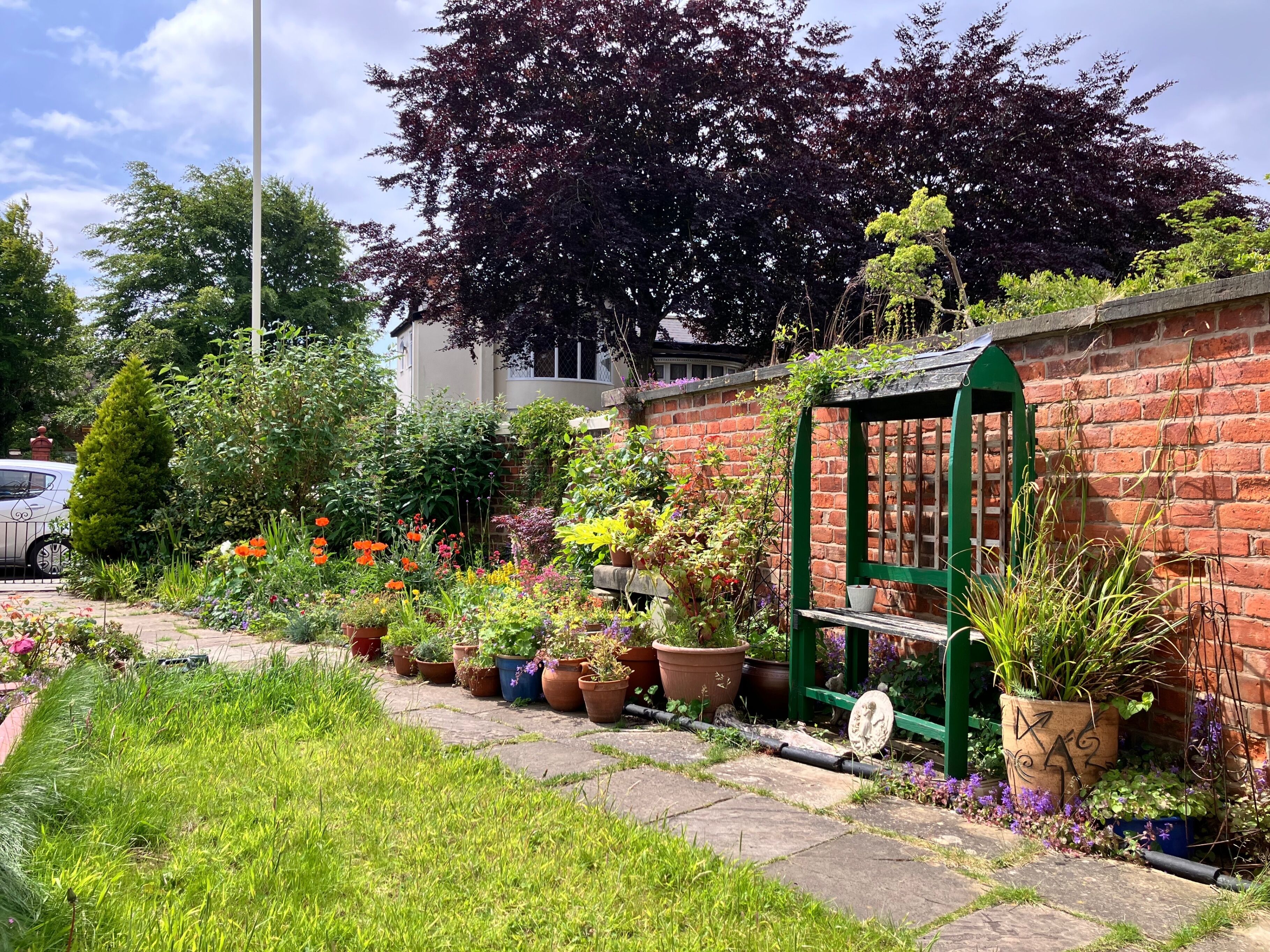 A garden with a brick wall, potted plants, and a green structure.
