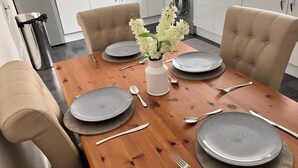 Taula de menjador preparada amb plats, coberts i un ram de flors en una cuina moderna.
