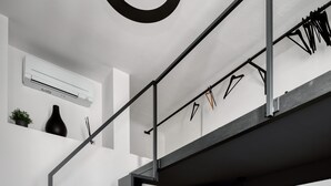 A modern staircase with a metal railing, an air conditioning unit, a black vase, and a small plant on the wall. - Farini 74 Design Apartment – Metro M3, WiFi, AC (Milan)