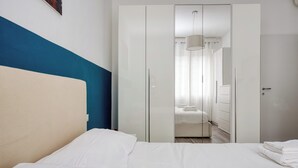 A hotel room with a bed, a wardrobe, and a bathroom visible through a mirrored closet door. - Stylish Flat Near San Siro – Metro, WiFi & AC (San Siro)
