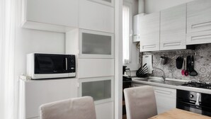 A modern kitchen with white cabinetry, a built-in microwave, a gas stove, and a sink. - Stylish Flat Near San Siro – Metro, WiFi & AC (San Siro)