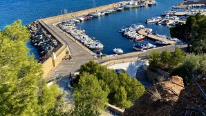 Un puerto deportivo con barcos amarrados, un muro de piedra y una vista despejada del mar.
