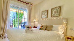 Una habitación de hotel con una cama grande, una mesita de noche, una lámpara y vistas al exterior a través de una ventana con cortinas.