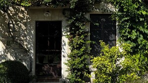 A building with a stone facade, a wooden door, and a window with shutters.