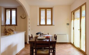 Un comedor con una mesa de madera, sillas, una cesta en la encimera y una ventana con persianas.