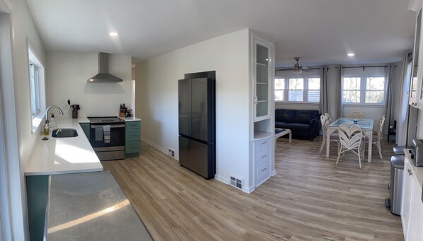 Una cocina moderna con horno empotrado, un refrigerador grande y un comedor con mesa y sillas.
