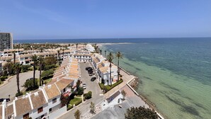 Ein Küstenwohngebiet mit Gebäuden, freiem Blick auf das Meer und einer Straße, die zum Strand führt.