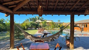 A wooden deck with a pool, a hammock, and outdoor furniture. - Pousada Refúgio Verde Trancoso (Porto Seguro)